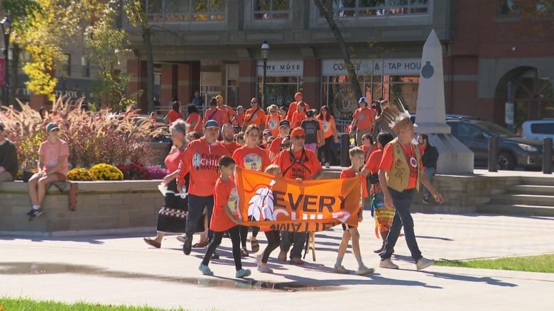 People wearing orange and holding 'Every Child Matters' banner 