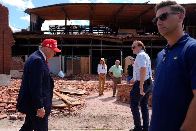 Trump in red cap touring disaster site