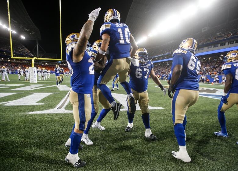 Football players in blue and white uniforms celebrate a touchdown on the field. 