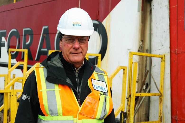 Man in construction vest, hard hat and safety goggles standing for picture