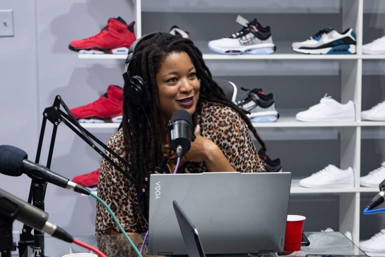 A woman sits behind a laptop in a sneaker shop.