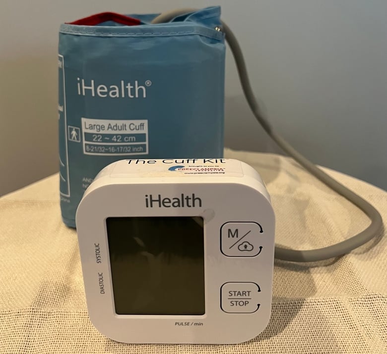 A blue blood pressure cuff sits behind a white monitor