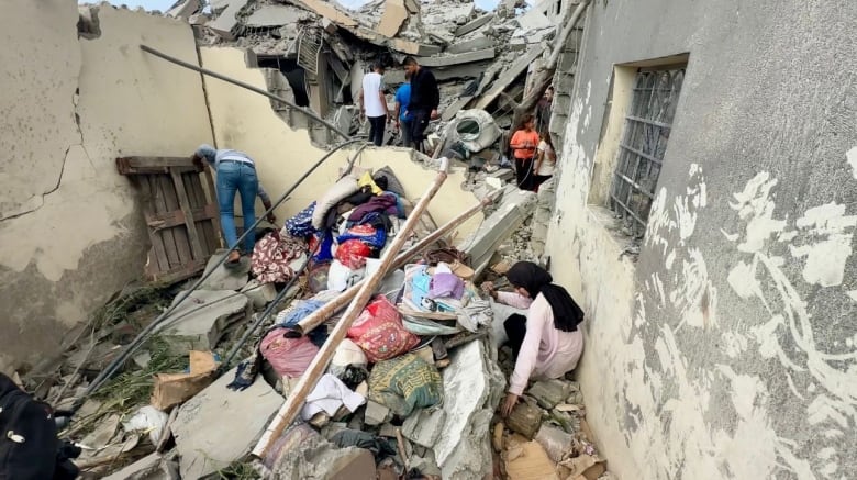 A woman sits in the middle of rubble.