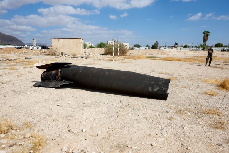 A member of Palestinian security forces stands near a projectile a day 