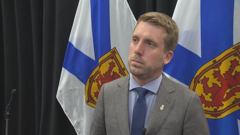 Man in suit stands near flags.