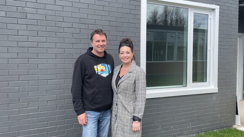 Portrait of a couple in front of their newly renovated building.