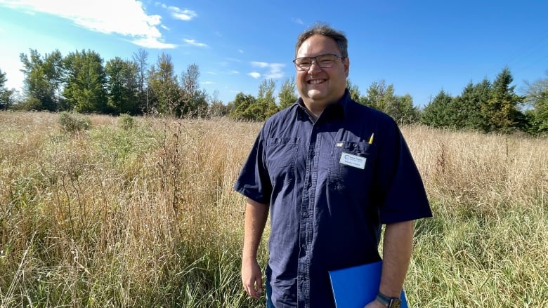 A conservation officer stands in a grassy field. 