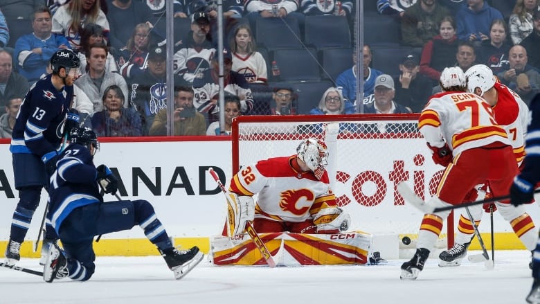 A hockey disks goes inside the net on with players around it.