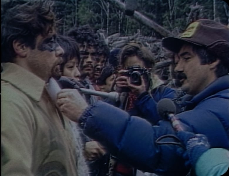 A line of people are surrounded by press people with mics and cameras.