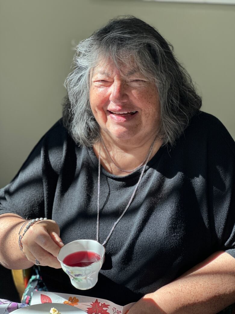 A woman holds a cup of tea.