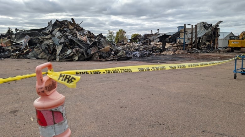 A huge pile of building rubble sits on the ground behind some police tape. 