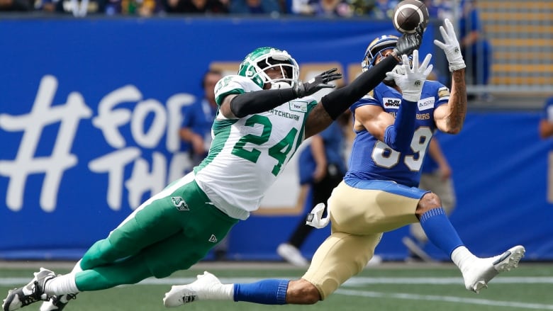 A Saskatchewan Roughrider player is seen knocking away as pass that is heading towards a Winnipeg Blue Bomber.