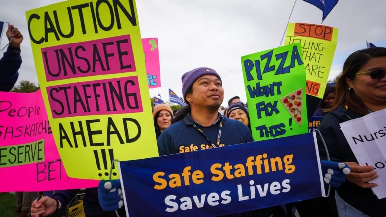 Several people hold signs calling for better health-care staffing.