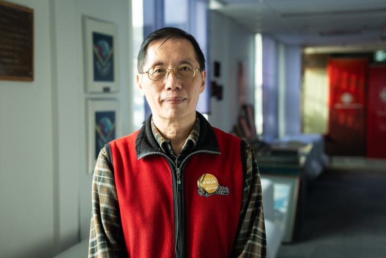 A man in a vest stands in an office hallway.