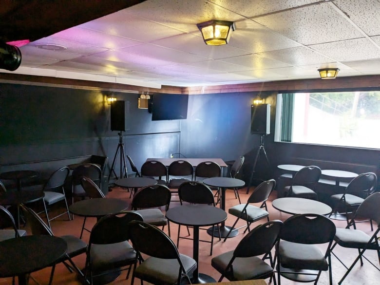 A room with scattered folding chairs and a small stage