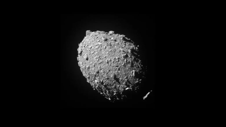 A grey rock sits in the blackness of space.