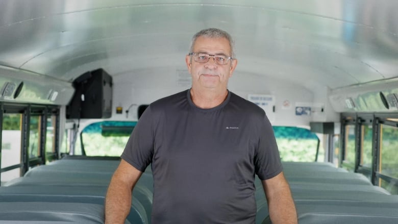 A man stands in a school bus, looking at the camera 