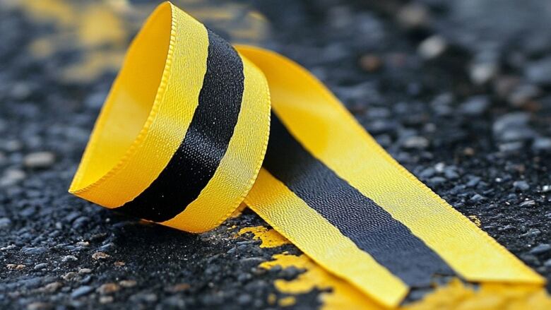 A black and yellow ribbon is placed on a road 