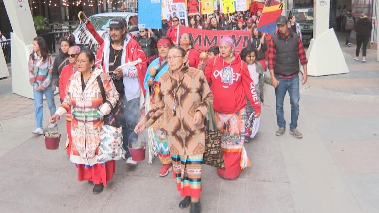 A group of people walk holding various signs.