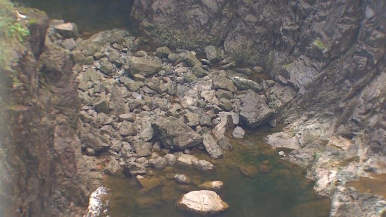 A low angle shot of a pile of rocks near a river. 