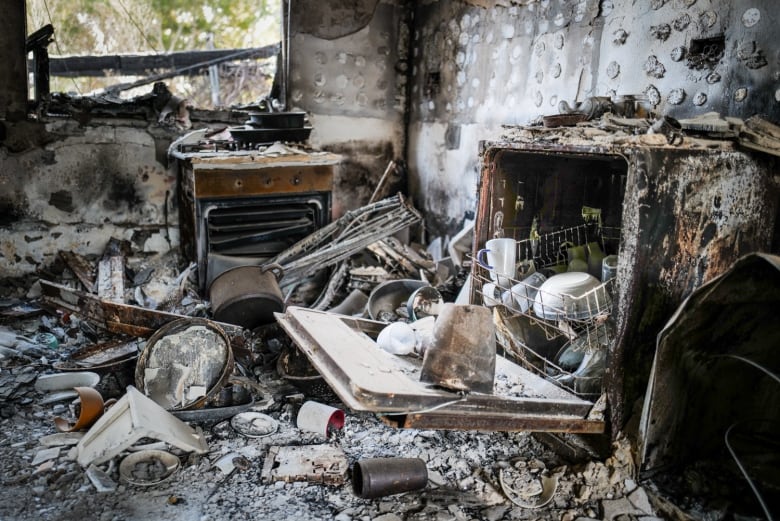 Burned kitchen appliances and debris are seen strewn inside a destroyed home.