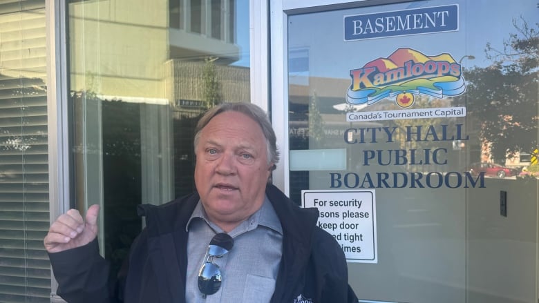 A man points to a room that reads 'City Hall Public Boardroom.'