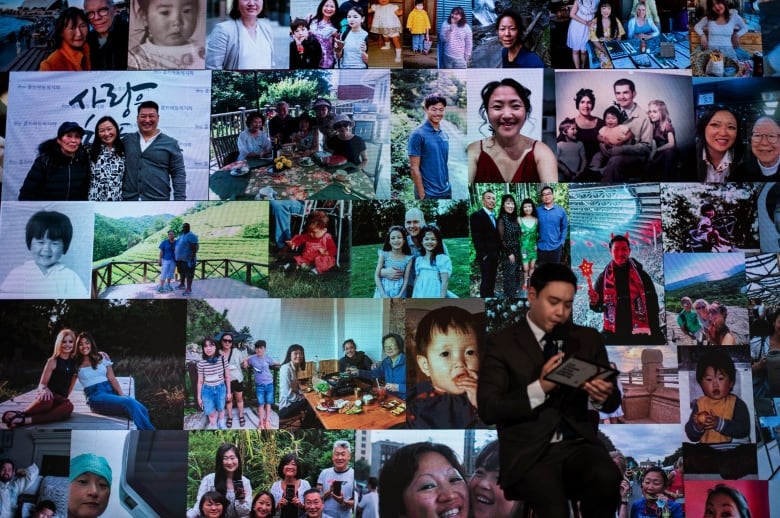 A cleanshaven Asian man speaks into a microphone in front of a large backdrop containing a mosaic of photographs of Asian people of all ages.