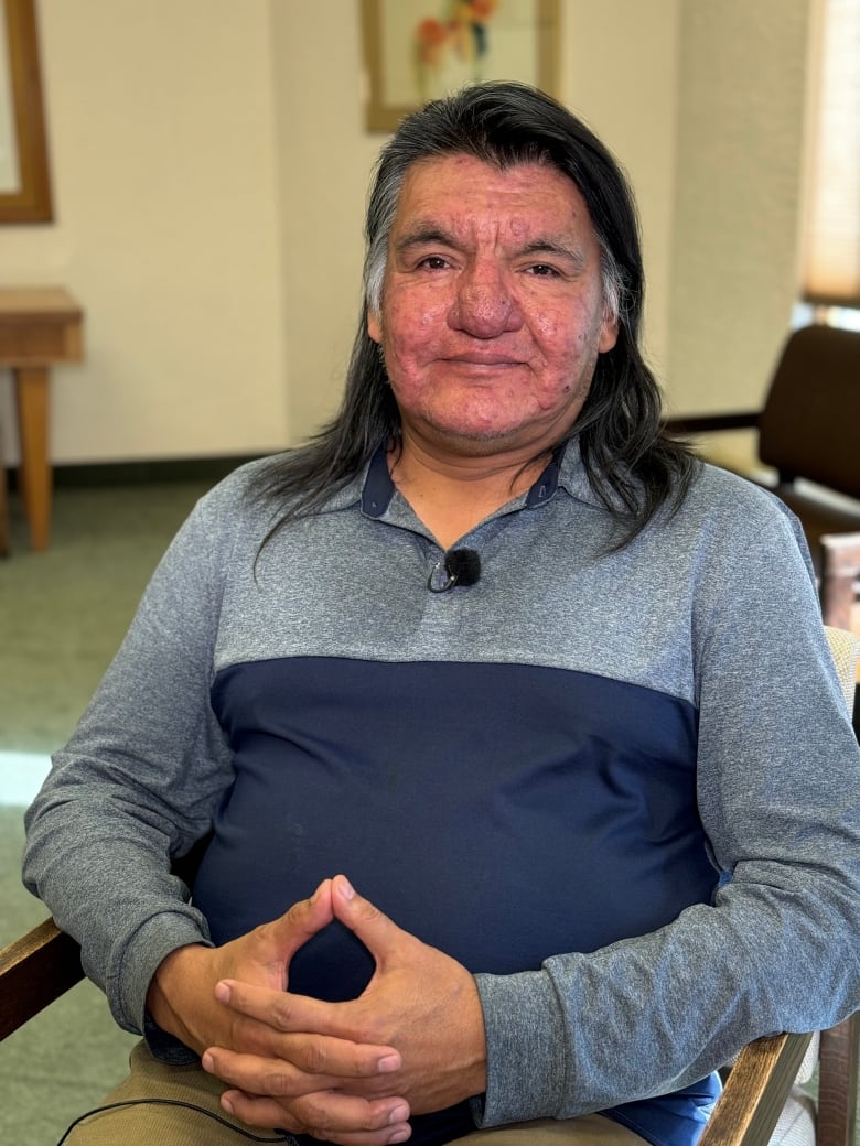 A man with long hair sitting in a chair.