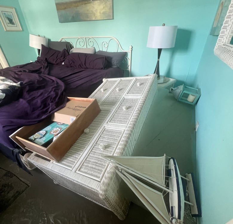 A bedroom with toppled furniture and muddy floors