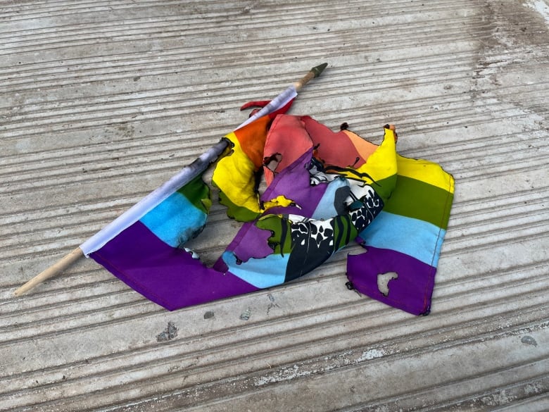 A burned two-spirit Pride flag sitting on a step.