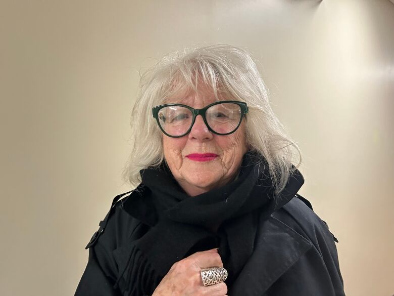 A white lady with white hair, wearing glasses.