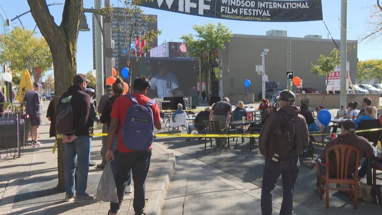 People watch a big screen outdoors.