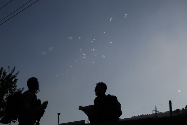 Members of the Israeli forces watch the Iron Dome air defense system firing to intercept rockets that were launched from Lebanon, in northern Israel, Wednesday, Oct. 9, 2024.