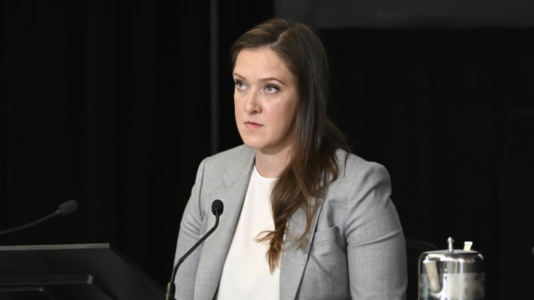 A woman sits before a microphone.