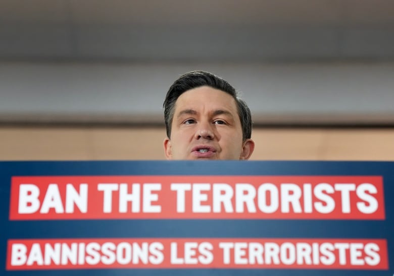 Conservative Leader Pierre Poilievre stands at a podium, his face is visible above a bilingual sign that says 