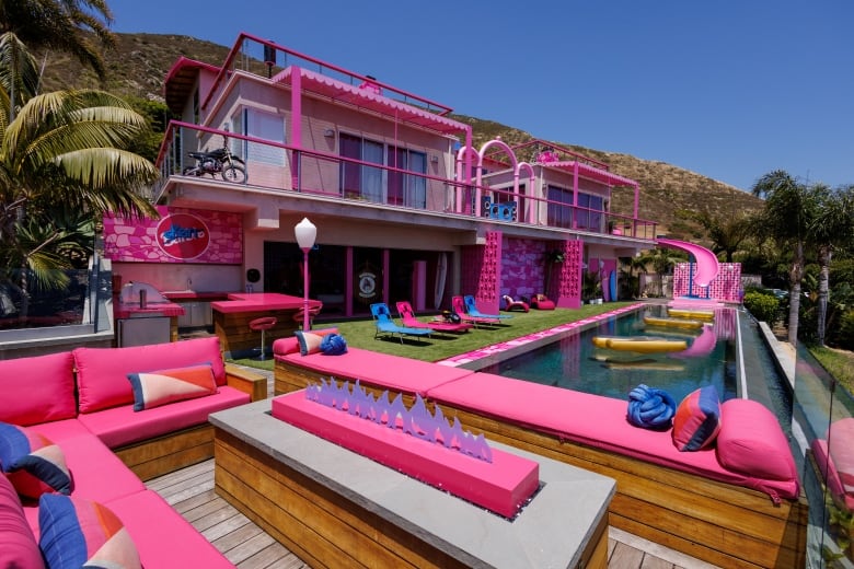 Outdoors shot of an expensive pool house with most of the architecture painted in bright pink.