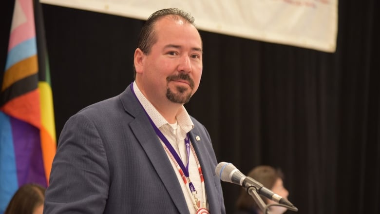 A man stands at a podium during a conference-style meeting.