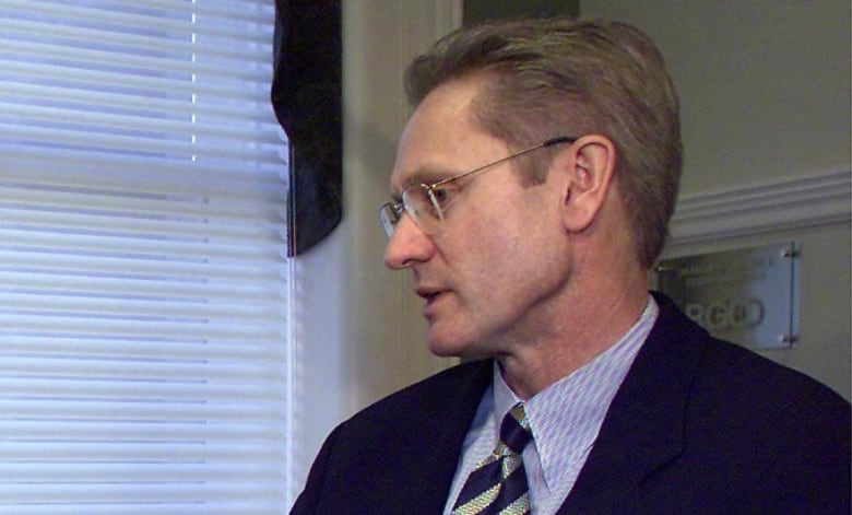 A man sits in an office in a chair.