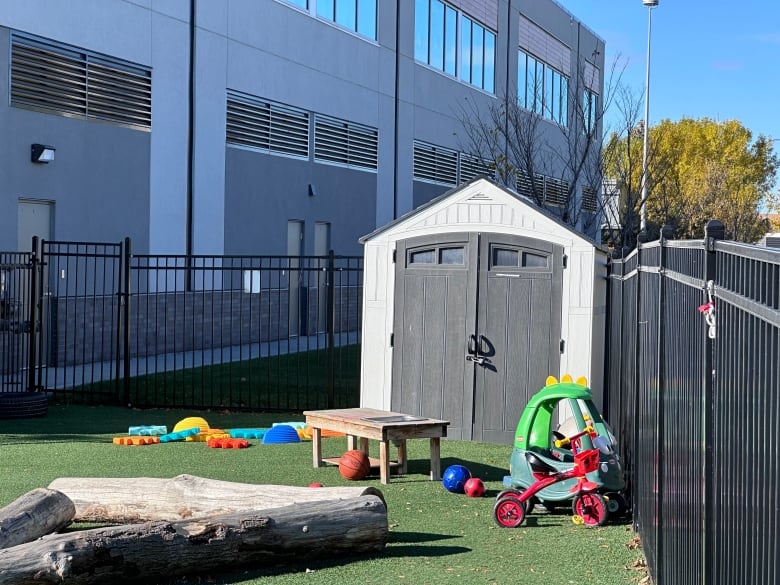 A fenced yard contains children's toys.