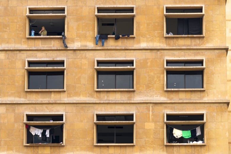 A woman drinks tea as she looks out from the window of a building in Dahiyeh, Beirut, Lebanon.