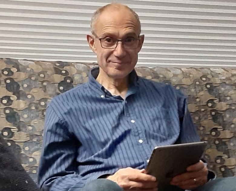 Man sitting on a couch with an iPad.