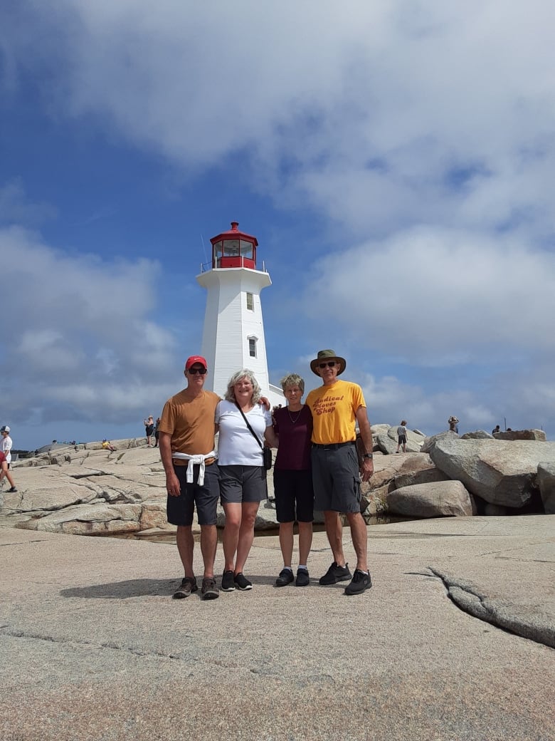 4 people pose in front of a lighthouse