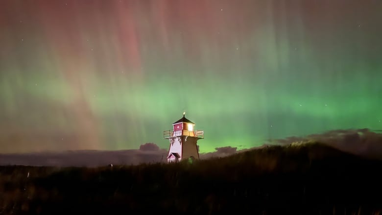 Covehead Lighthouse shines against a background of red and green northern lights.