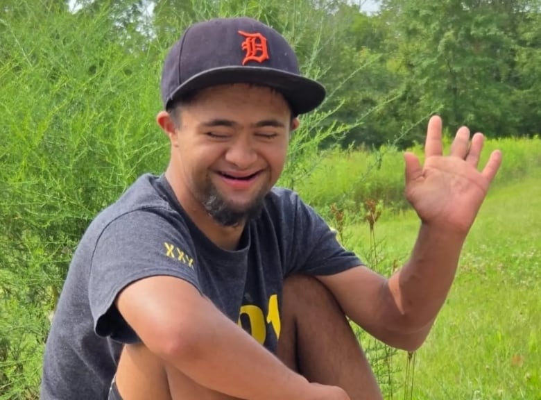 A child with Down syndrome smiles and waves.