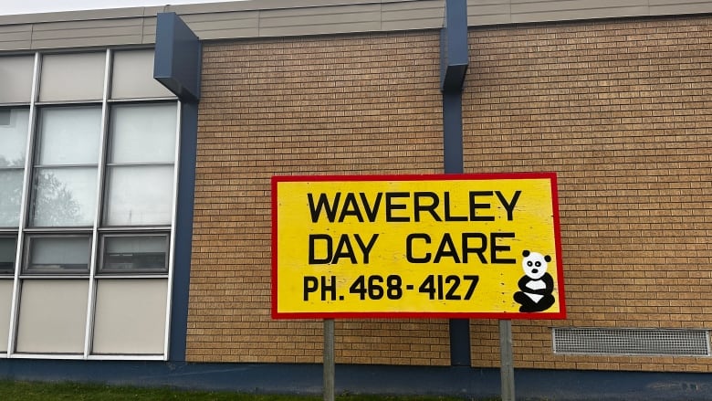 A photo of a yellow sign that reads waverley day care. It's on a red brick building.