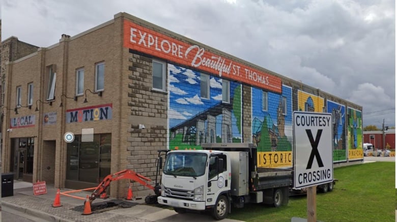 The side of brick building is seen with a colourful mural painted on the side.