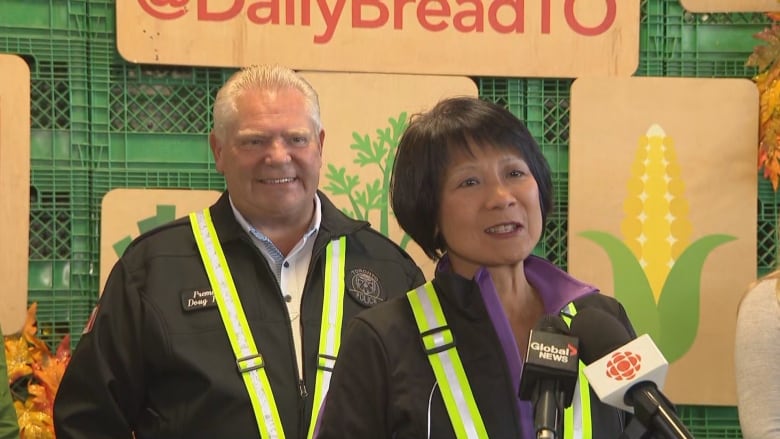 Olivia Chow speakes at a microphone, with Doug Ford standing behind her, to the left.