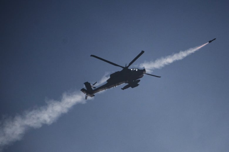 A military helicopter fires a missile.