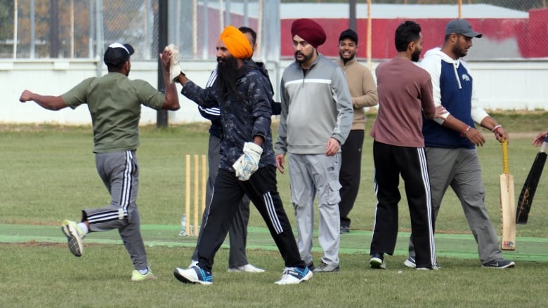 A person high-fiving another one wearing some gloves while people around them watch