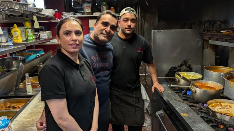 Three people in a restaurant kitchen.